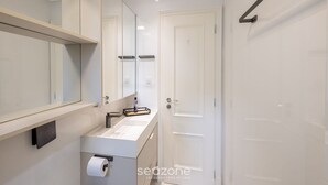 Un baño moderno con un espejo grande, un lavabo blanco y una puerta.