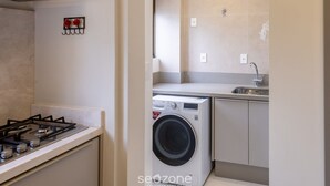 Una cocina compacta con estufa a gas, lavadora y pileta.