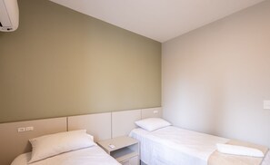 A hotel room with two single beds, a bedside table with a phone, and a wall-mounted air conditioner. - 3br Apt Sea View BBQ Garage - BC Vld1002 (Balneário Camboriú)