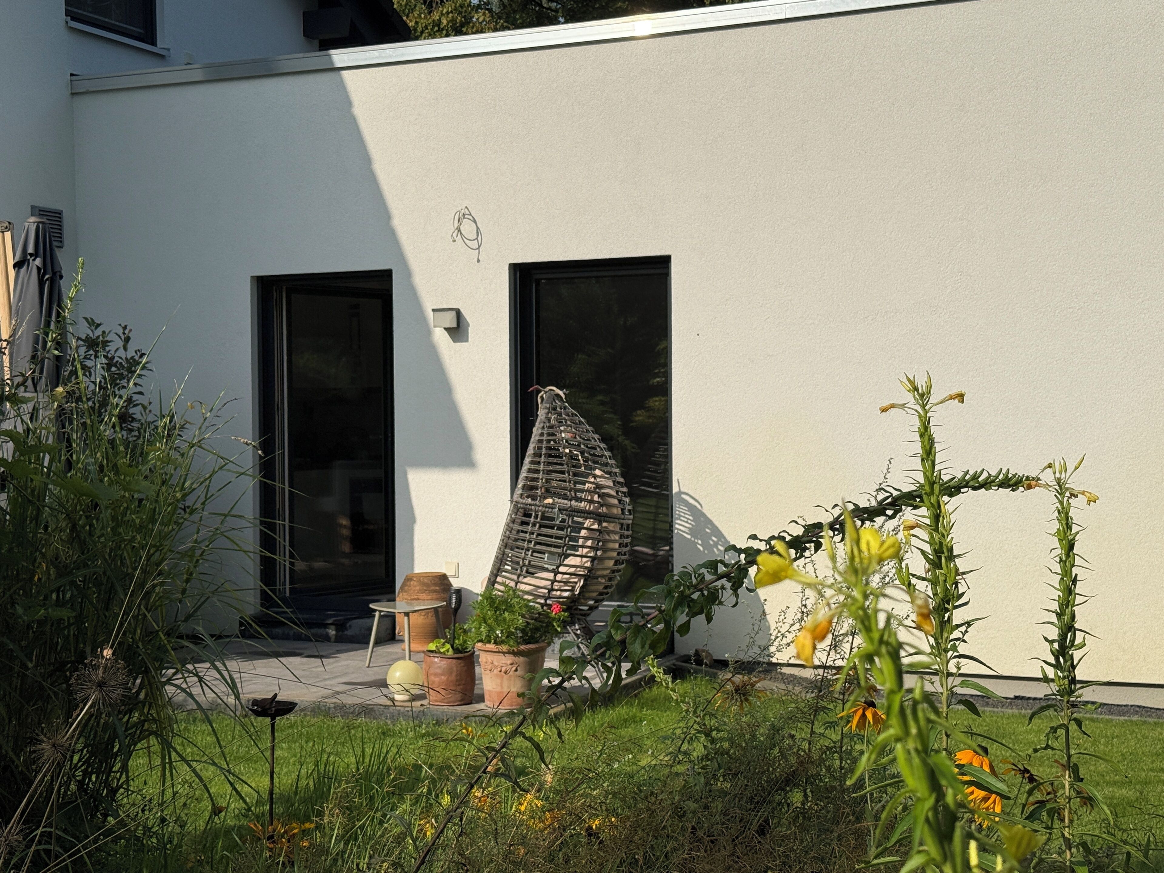 Ein modernes Gebäude mit zwei Türen, einer Wendeltreppe und Topfpflanzen im Vordergrund.
