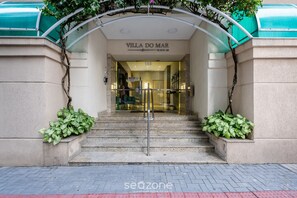 The entrance to Villa do Mar, featuring a set of stone steps, a glass door, and a metal gate. - Stay Steps From the sea in Meia Praia - VIM (Itapema)