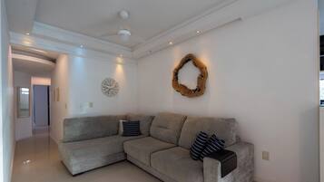 A modern living room with a grey sectional sofa, a decorative wooden wall piece, and recessed ceiling lighting.