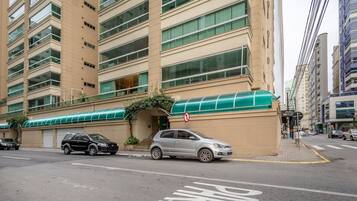 Um edifício de vários andares com toldo verde e placa de proibido estacionar.