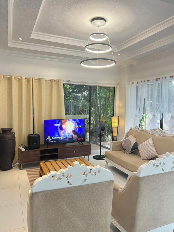 A living room with a television, sofa, and a fan.
