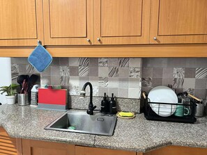 Una cocina con armarios de madera, encimera de granito, pileta de acero inoxidable y salpicadero de azulejos.