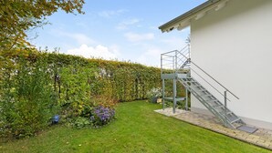 A garden with a metal staircase leading to a building. - Apartment 'Monte Fiori' with Balcony and Wi-Fi (Anzing)
