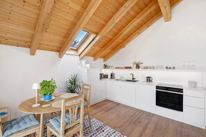 Una cocina moderna con gabinetes blancos, horno negro y tragaluz.