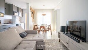 Una sala moderna con sofá, televisor y comedor.