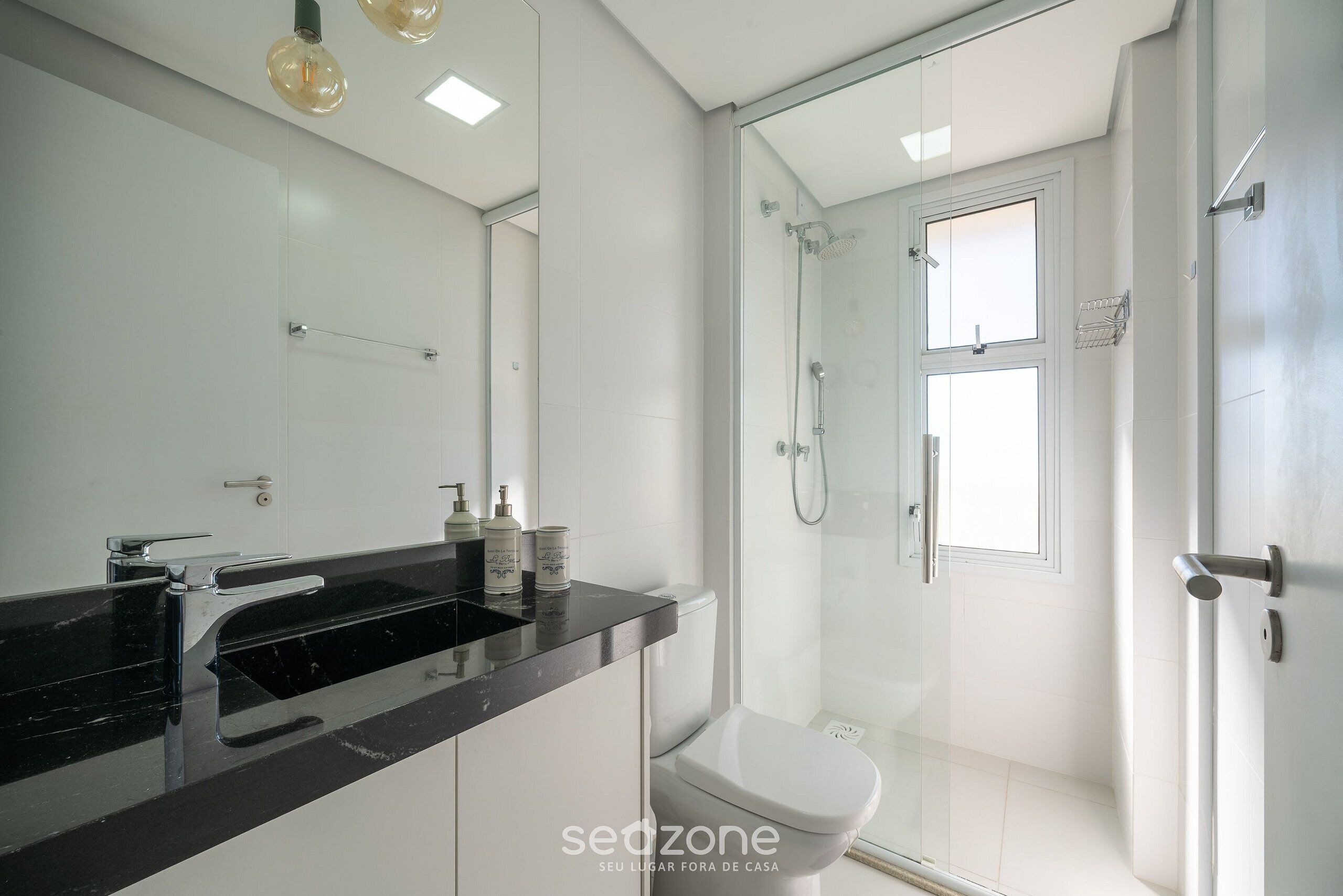 A modern bathroom with a black countertop, a toilet, and a glass-enclosed shower.