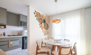 Une cuisine moderne équipée d’un four à micro-ondes, d’une cuisinière et d’un réfrigérateur. On y trouve également un coin repas avec une table ronde et des chaises.