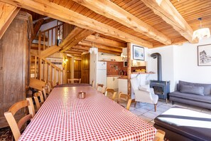 A wooden interior with a dining table, chairs, a sofa, and a fireplace.