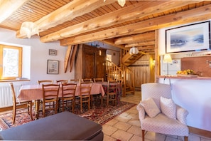 A wooden interior with a dining area, staircase, and a bar area.