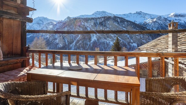 Un balcon en bois offrant une vue sur des montagnes enneigées.
