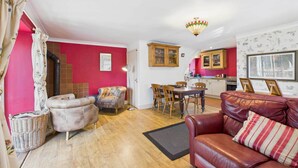 Una sala de estar con un sofá rojo, un sofá de cuero y una zona de comedor con sillas de madera y una mesa.