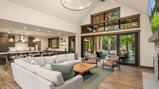 A spacious living area with a large sofa, a coffee table, and a dining area with a kitchen in the background. - Private Pool * Fantastic Outdoor Living in Suncadia! (Cle Elum)
