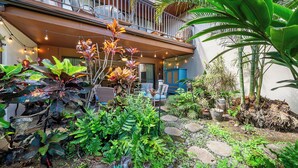 Ein Balkon mit Lichterketten, Topfpflanzen und Gartenmöbeln.