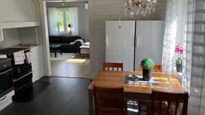 A dining area with a wooden table and chairs, a chandelier, and a potted plant.