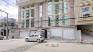 A multi-story building with large windows and a garage entrance. - 3-suite apt 280m From sea in Itapema Vga1002 (Itapema)