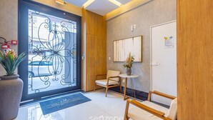 A reception area with a modern design, including a wooden reception desk, a seating area with chairs, and a decorative metal gate. - 3-suite apt 280m From sea in Itapema Vga1002 (Itapema)