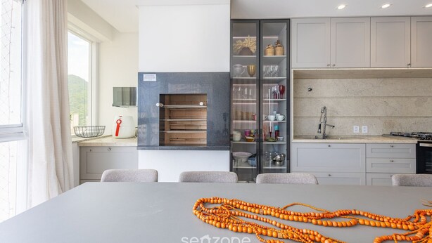 A modern kitchen with a built-in oven, a dining area with a table, and a view of the outdoors. - 3-suite apt 280m From sea in Itapema Vga1002 (Itapema)