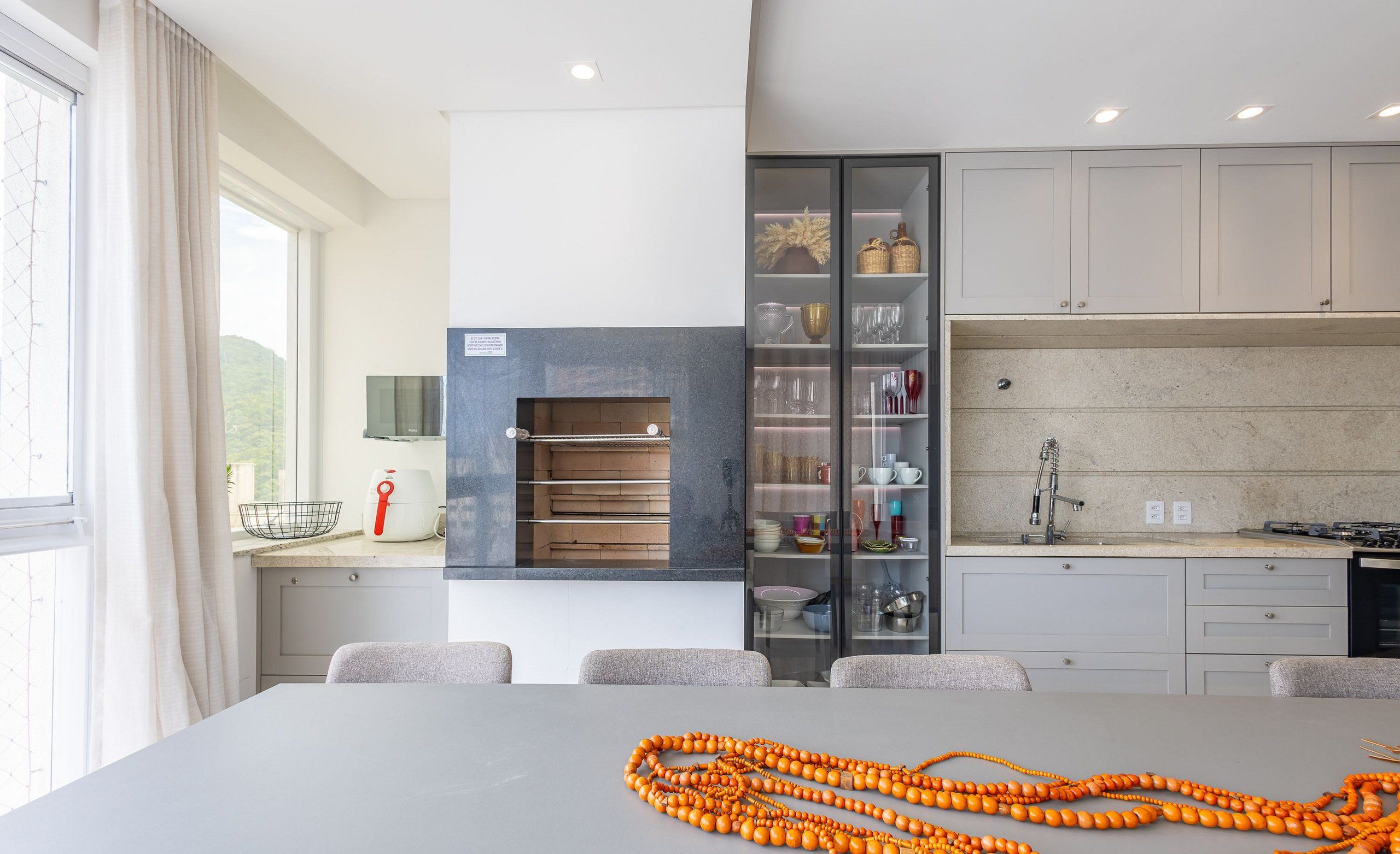 A modern kitchen with a built-in oven, a dining area with a table, and a view of the outdoors.