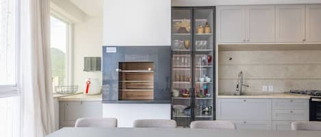 A modern kitchen with a built-in oven, a dining area with a table, and a view of the outdoors.