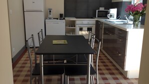 Una cocina moderna con una mesa de comedor, sillas, un refrigerador, un microondas y una cafetera.