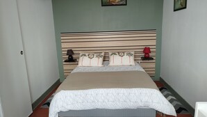 Un dormitorio con cama, mesita de noche, lámpara y un cuadro en la pared.