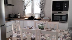 Une cuisine compacte comprenant une table à manger, des chaises, un réfrigérateur, un four à micro-ondes et un four encastré.