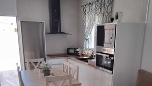 Une cuisine compacte comprenant une table à manger, des chaises, un canapé et un four encastré.
