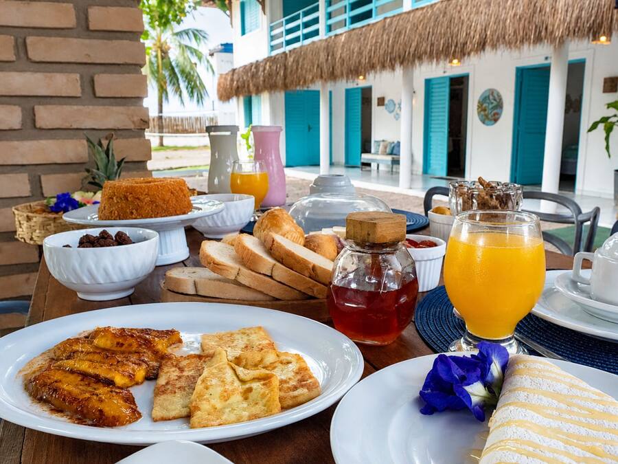 Una mesa de desayuno con diversas comidas, un vaso de jugo de naranja y una cámara sobre un trípode.