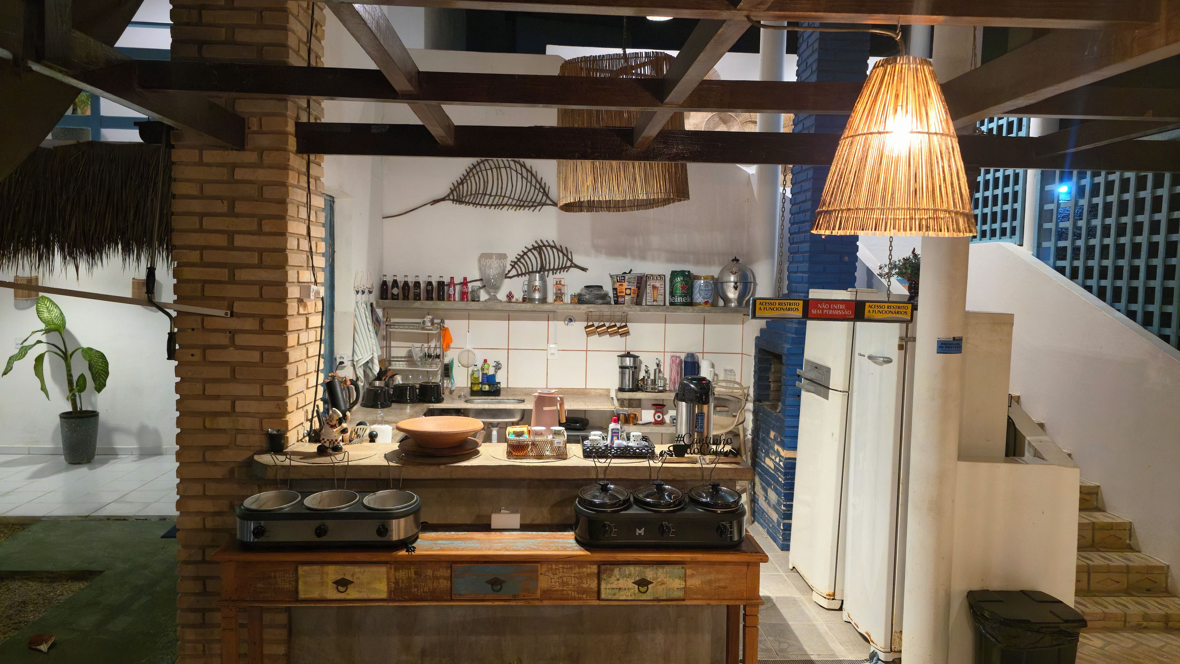 Una cocina con pared de ladrillo, lámpara colgante y encimera con varios utensilios de cocina.