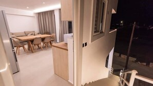 Een modern interieur met een eethoek, een trap en uitzicht op de nacht.