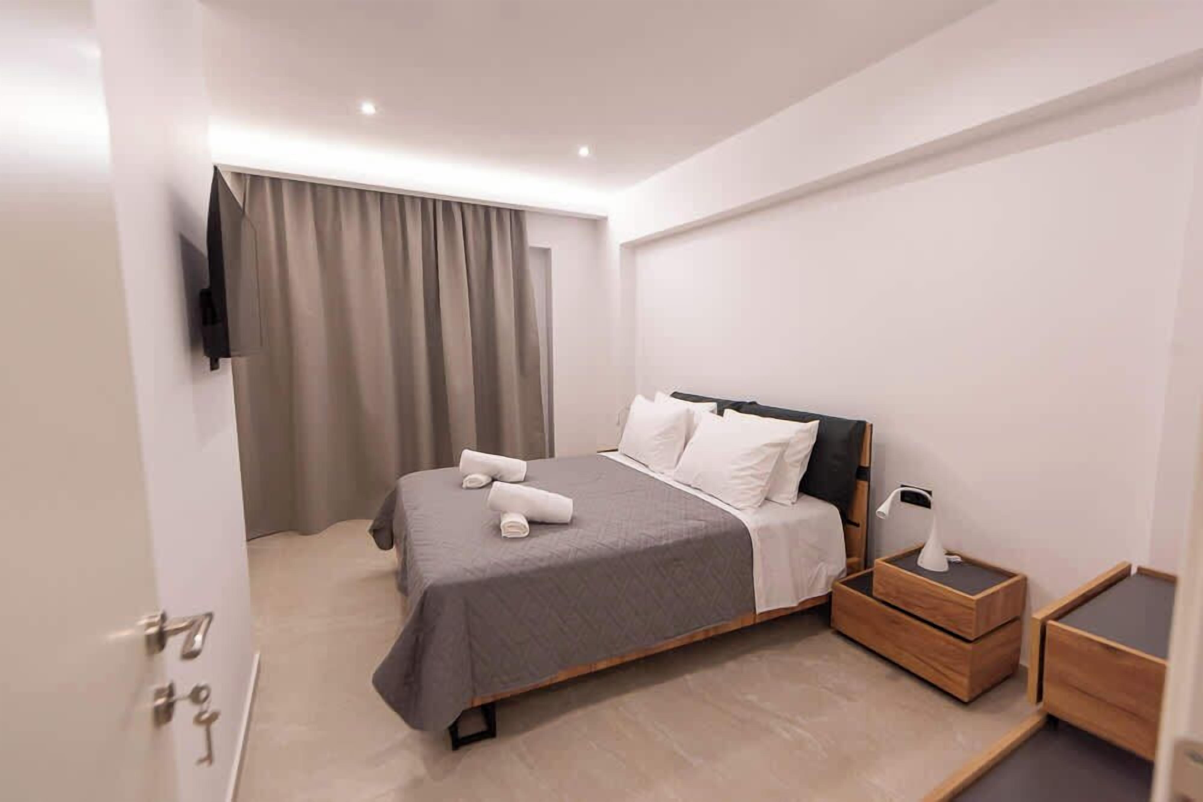 Ein modernes Hotelzimmer mit einem Bett, einem Nachttisch mit Lampe und einem an der Wand befestigten Fernseher.