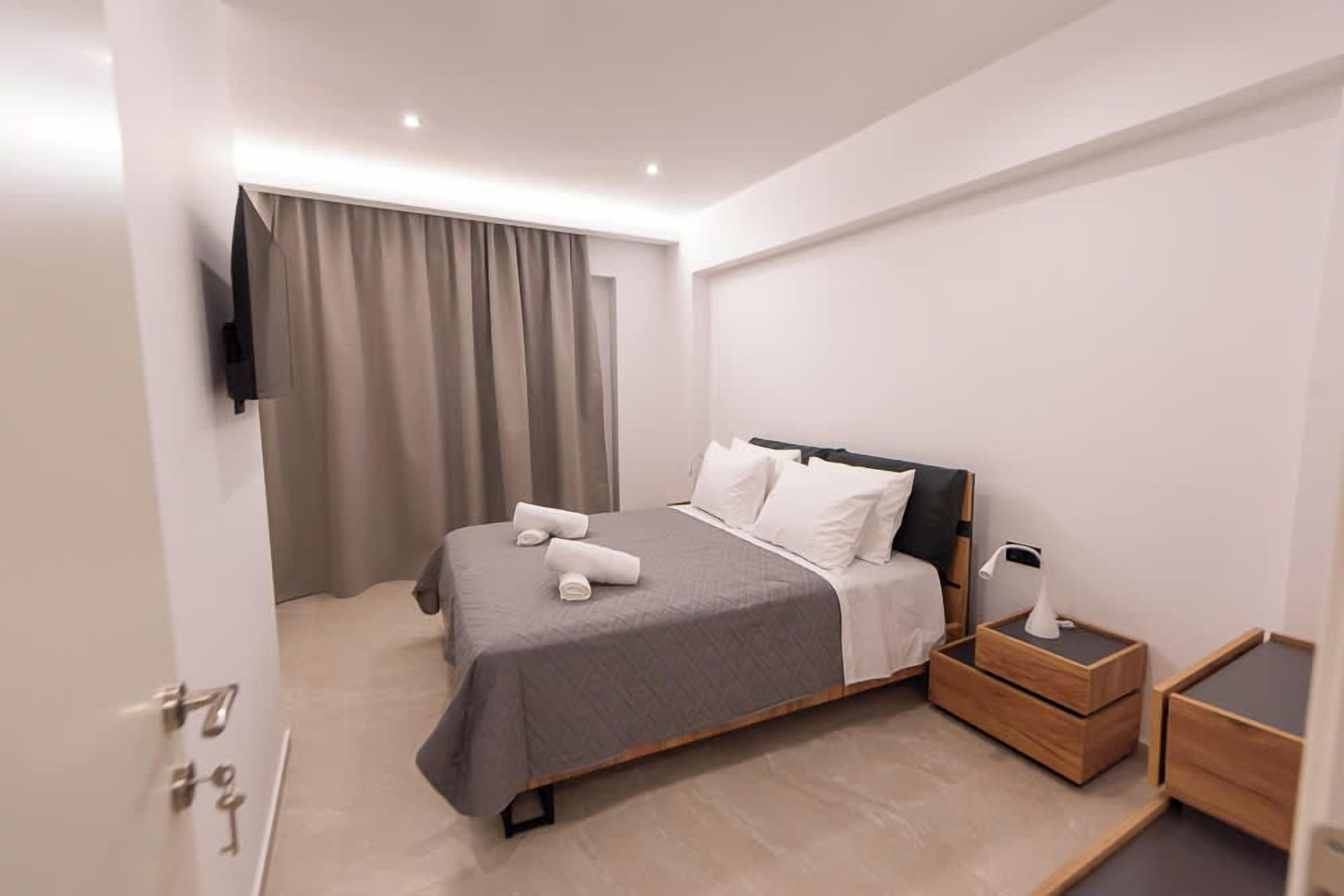 Ein modernes Hotelzimmer mit einem Bett, einem Nachttisch mit Lampe und einem an der Wand befestigten Fernseher.