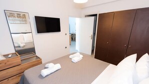 A modern hotel room with a large bed, a wooden dresser, a flat-screen TV, and a wardrobe. - Sinani Villas Rhodes - Private Family Getaway (Afantou)