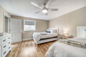 A bedroom with a bed, a desk, a chair, a ceiling fan, and a window with blinds. - The Sandbar: Large Vacation Home with Year-Round Pool Access (South Haven)