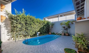 A swimming pool with a tiled deck, surrounded by potted plants and a hedge. - 2BR House w/ Pool & BBQ in Penha Tzs210 (Penha)