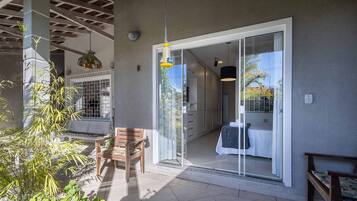 Un espacio exterior moderno con un ventanal corredera que da a una habitación, un banco de madera y una lámpara colgante.