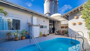 Ein Swimmingpool mit einer Leiter, umgeben von Topfpflanzen und Gartenmöbeln.