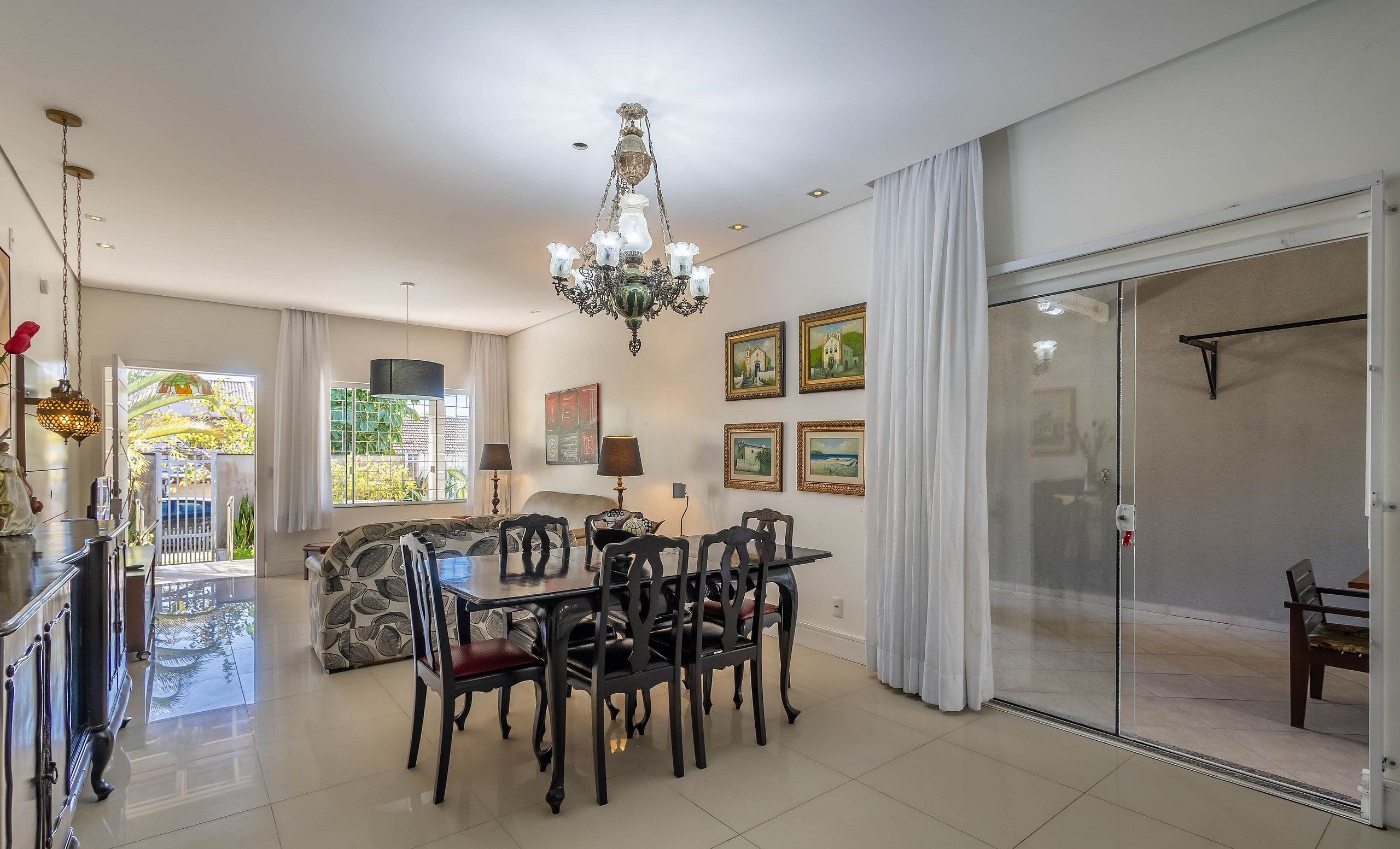 Un comedor con candelabro, mesa, sillas y obras de arte en las paredes.