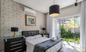A bedroom with a bed, bedside tables, a painting, and a view of greenery outside. - 2BR House w/ Pool & BBQ in Penha Tzs210 (Penha)