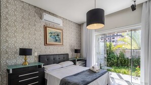 Ein Schlafzimmer mit Bett, Nachttischen, einem Gemälde und Blick auf Grün.