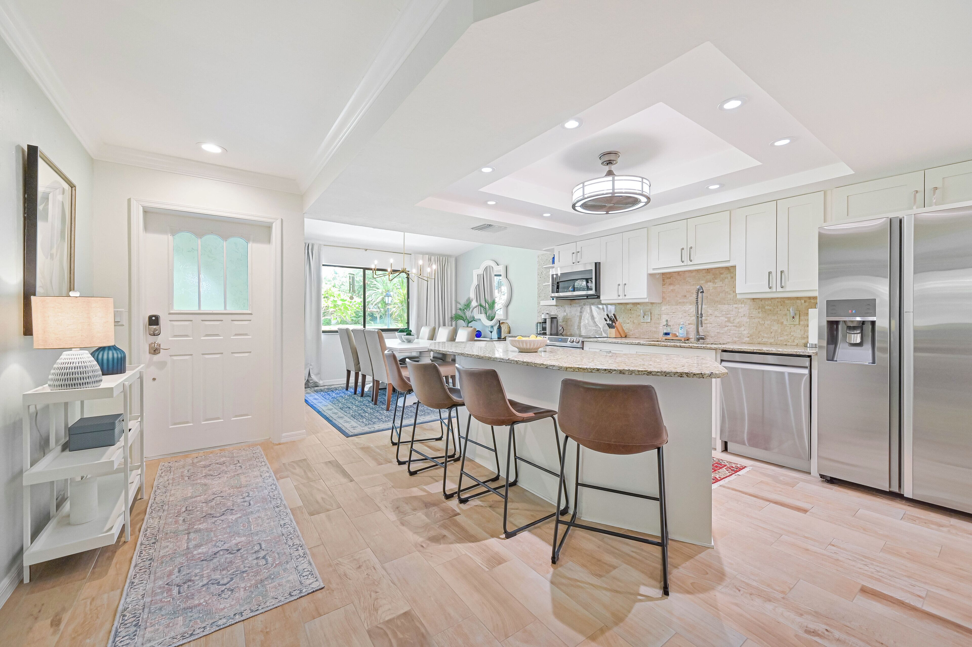 A modern kitchen with a central island, stainless steel appliances, and a bar area with stools.