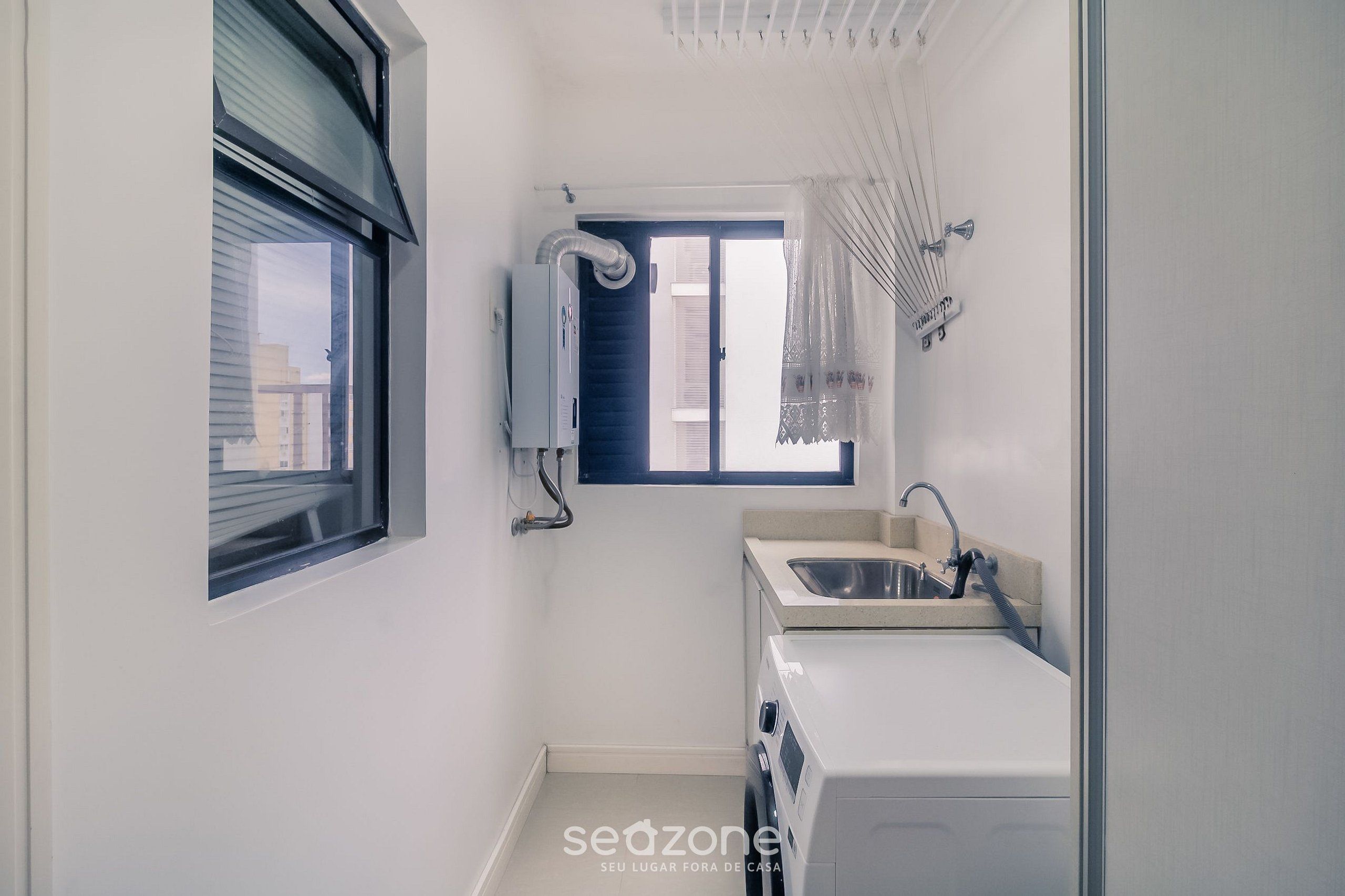 Une petite salle de bain avec une fenêtre, un lave-linge encastré et un lavabo.