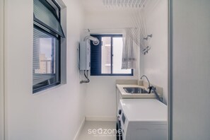 A compact bathroom with a window, a built-in washing machine, and a sink. - 3BR Apt w/ BBQ 170m From Beach Tsf1302 (Balneário Camboriú)