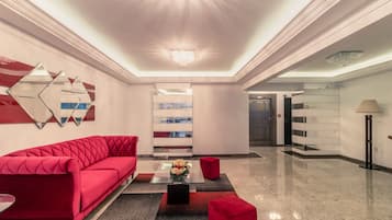 A modern lobby with a red sofa, a glass coffee table, and a chandelier.