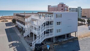 Un edificio de varios pisos con un balcón en la planta baja, situado cerca de la playa.