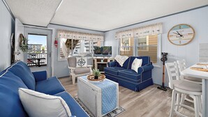 Un espacio habitable compacto con un sofá, una mesa pequeña, un televisor y una zona de comedor.