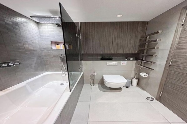 Un baño moderno con ducha envuelta en vidrio, inodoro blanco y lavabo integrado.